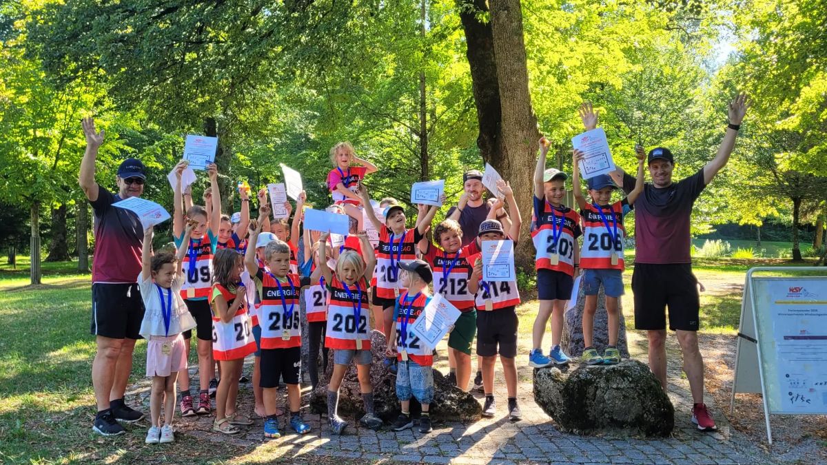 Kinder und Betreuer beim Gruppenfoto im Park, die Urkunden in die Höhe gestreckt