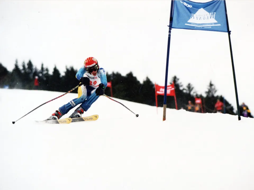 Andreas Waldenhofer mit rotem Helm fährt auf ein blaues Riesentorlauftor zu.
