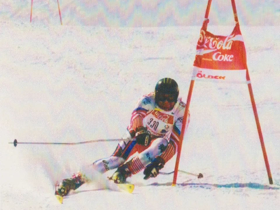Helmut Stadler mit Startnummer 330 in tiefer Hocke an einem Riesentorlauftor.