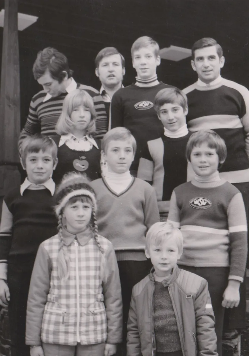 Kinder und Jugendliche mit ihren Betreuern vor einer Holzhütte, einige tragen Pullover mit dem WSV-Abzeichen.